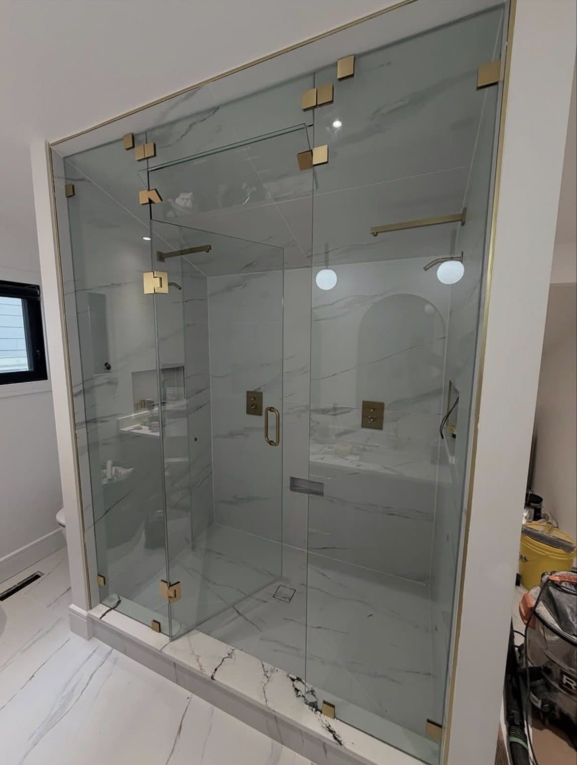Frameless glass shower with brushed brass hinges and handle