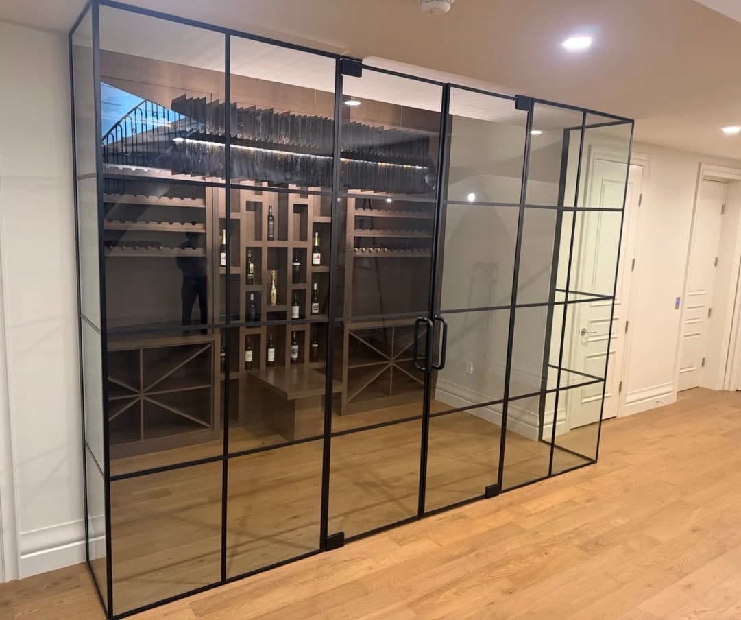 Black-framed glass wine room with double doors, seen at an angle